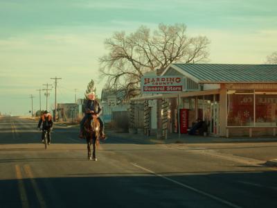 mand rider på hest gennem en lille amerikansk by